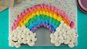 Pastel arcoiris con cupcakes en su decoración: Originalidad y diversión garantizada